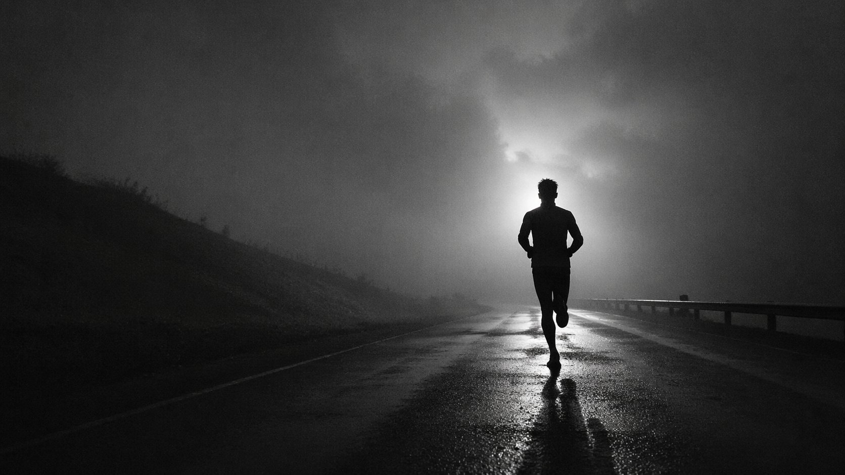 Silhouette d'un athlète courant seul au lever du jour sur une route mouillée — FORTE Performance